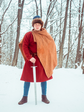 Frankish warrior in historical costume with sword in winter forestの写真素材