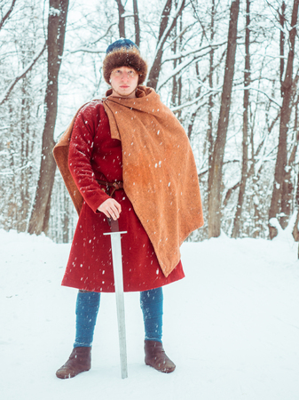 Frankish warrior in historical costume with sword in winter forestの写真素材
