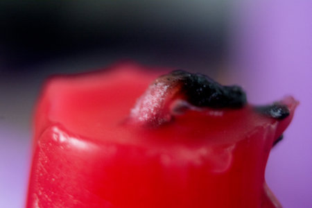 Close up shot of a red wax candle on a purple background.の写真素材