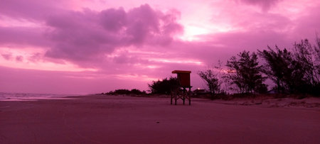 Sunset on the beach with a lifeguard hut in the foregroundの写真素材