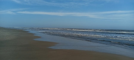 Beautiful panoramic view of a sandy beach with waves breaking on the shoreの写真素材