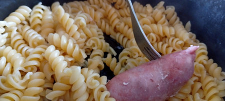 Fusilli pasta with ham and tomato sauce in a pan.の写真素材