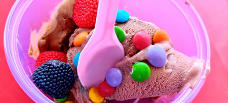 ice cream in plastic container with colorful candies on pink background.の写真素材