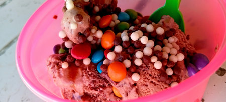 Close up of ice cream in pink bowl with colorful candies.の写真素材