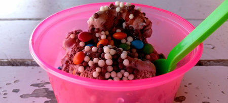 Colorful chocolate ice cream in a pink bucket on a wooden tableの写真素材