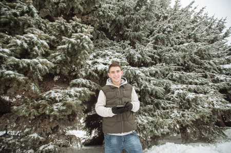 Outdoor winter portrait for young handsome man. Beautiful teenager in his jacket and vest posing on...