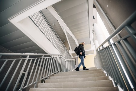 Profile of attractive happy young man with beard standing in winter urban. Glasses, jacket, hat. Color.の写真素材