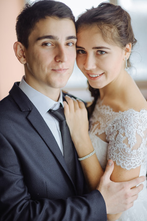 Bride and groom at wedding day walking indoors in style hall. Bridal couple. Happy newlywed woman and man embracing to hotel. Loving wedding twin.の写真素材