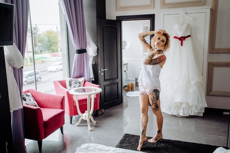 Closeup portrait tattoo red hair girl. Fashion concept: portrait of young beautiful woman wearing lingerie in bedroom of apartaments hotel with cool wedding dres.の写真素材