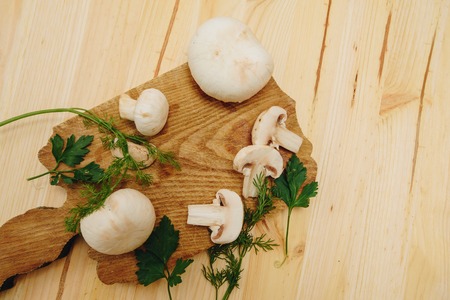 Royal mushrooms with a sprig of parsley and dill on an old wooden table in rustic style, selective focus.の写真素材