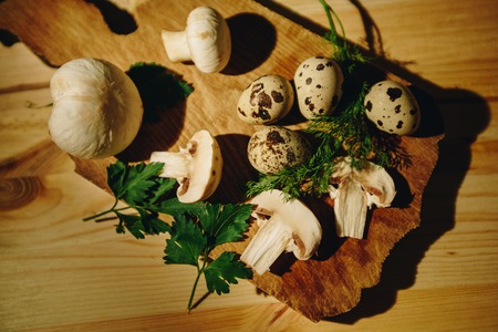 Royal mushrooms with a sprig of parsley and dill, eggs on an old wooden table in rustic style, selective focus.の写真素材