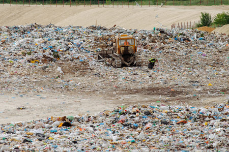 Truck working in landfill with birds looking for food. Garbage on the city dump. Soil pollution. Environmental protection. Waste.の写真素材