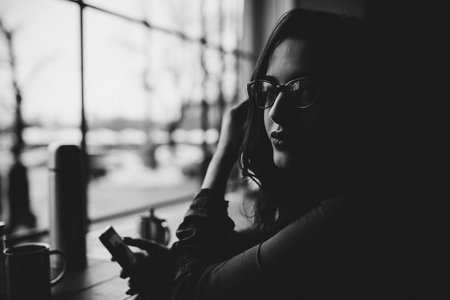 Fashion consept: beatiful young girl with long hair, glasses, red lips standing near modern wall wearing in green suit and grey jeans. She wanted talking on phone.の写真素材