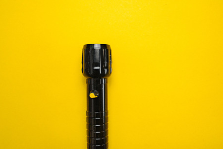 Travel and Search. Close-up of a flashlight on yellow background.の写真素材
