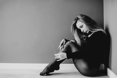 Skillfull modern dancer sitting on the parter in the dance studio. Contrast background.