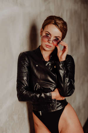 Portrait of blond charming woman against loft wall. Attractive young woman with sexy shapely forms, loose wavy hair, and slim body is posing in the black underwear. Studio photoshoot.の写真素材