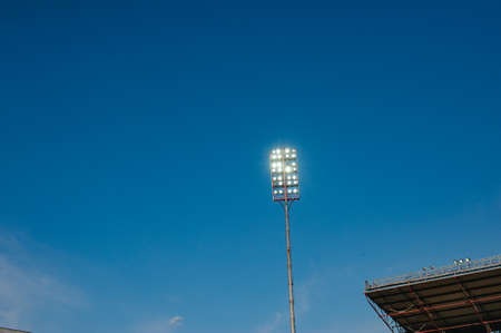 Floodlights with a metal pole for the sports arena. Tall high outdoor stadium spotlights on rigid frame construction with blue sky backgroundの写真素材