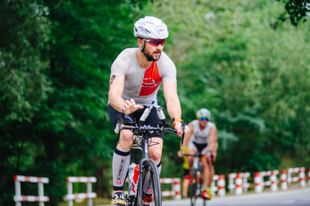 KHARKIV, UKRAINE - August 2, 2020: Triathon biking cyclist triathlete riding racing bike during ironman competition. Road cycling athlete in tri suit and helmet. Public events are allowed. Europe sport during CV pandemic.のeditorial素材