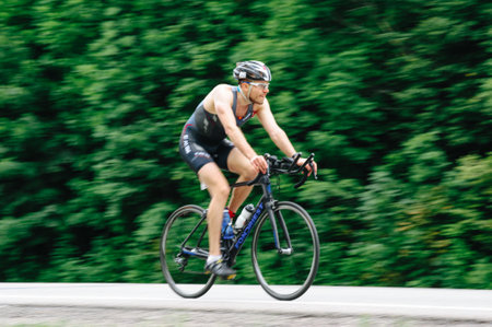 KHARKIV, UKRAINE - August 2, 2020: Triathon biking cyclist triathlete riding racing bike during ironman competition. Road cycling athlete in tri suit and helmet. Public events are allowed. Europe sport during CV pandemic.のeditorial素材