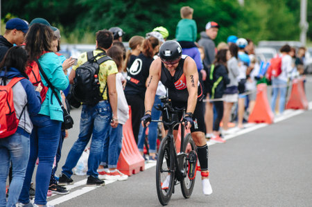 KHARKIV, UKRAINE - August 2, 2020: Triathon biking cyclist triathlete riding racing bike during ironman competition. Road cycling athlete in tri suit and helmet. Public events are allowed. Europe sport during CV pandemic.のeditorial素材