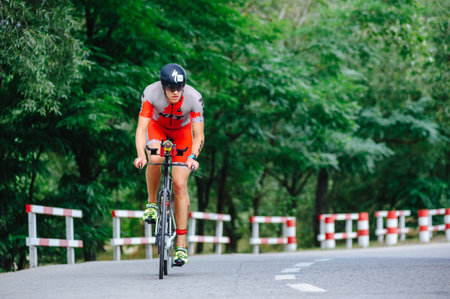 KHARKIV, UKRAINE - August 2, 2020: Triathon biking cyclist triathlete riding racing bike during ironman competition. Road cycling athlete in tri suit and helmet. Public events are allowed. Europe sport during CV pandemic.のeditorial素材