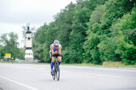 KHARKIV, UKRAINE - August 2, 2020: Triathon biking cyclist triathlete riding racing bike during ironman competition. Road cycling athlete in tri suit and helmet. Public events are allowed. Europe sport during CV pandemic.のeditorial素材