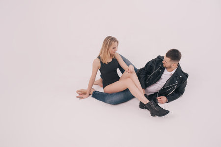 Happy time. Beautiful young couple sitting on floor in studio. Man wearing in denim clothes and...