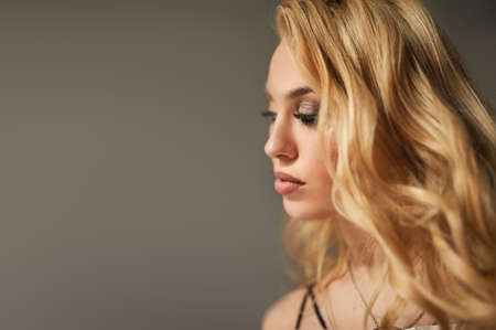 Fashion, beauty and make up. Beautiful side portrait of blonde model girl with long curly hair.の写真素材