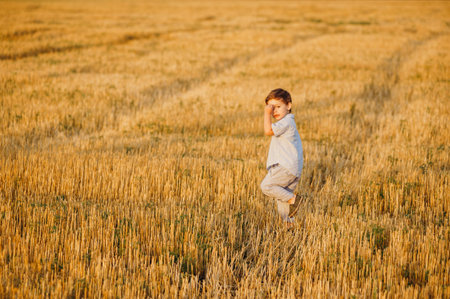 Emotional little adorable boy playing in the field in the warm rays of the setting sun in the...