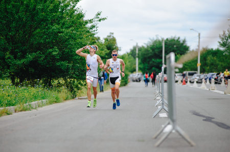 KHARKIV, UKRAINE - AUGUST 2, 2020: Kharkiv triathlon Iron Way. The runner after the transition to cycling. Triathlete man running in triathlon suit training for ironman race.のeditorial素材