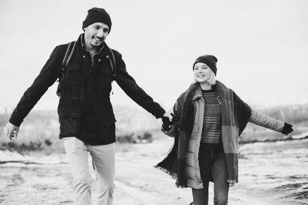 Black and white. Cool valentine. Happy loving couple walking in snowy winter field, spending Christmas vacation together. Outdoor seasonal activities. Lifestyle capture.の写真素材