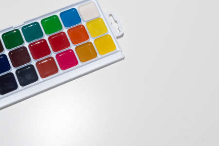Top view of set of watercolor paints in a box, isolated on white. Back to school concept. Concept for a painting school or art store. Hobby concept for children and adults. Minimalism, top view, copy space.の写真素材