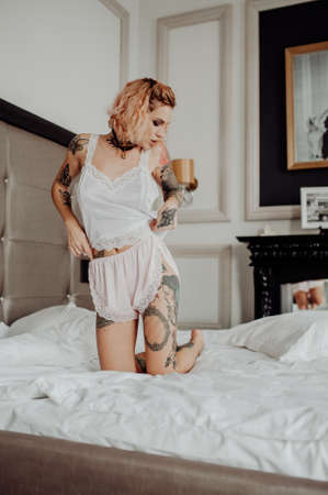 Portrait of a happy beautiful girl with tattoos. The woman is in the bed.の写真素材