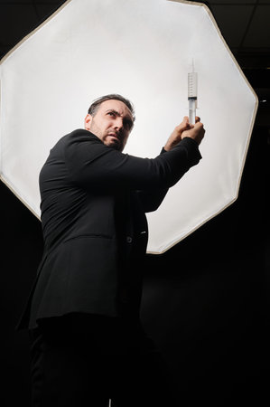 Medical warrior. The vaccination of happy. Scientist business man in black suit with syringe in hand welcoming vaccine shot. The medical concept.の写真素材