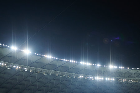 The stadium lit floodlighting into the darkness of the evening. Bokeh effect.