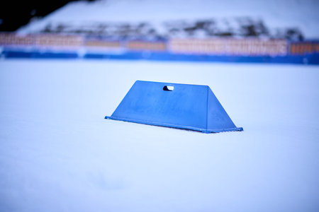 Minimal close-up of a blue plastic course marker on fresh snow at the Chiemgau Arena,...