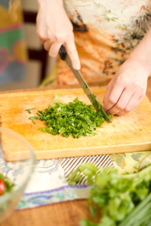 Woman s hands cutting fresh onions, dill, parsley on kitchen  Focus on green vegetables  The concept of food and a healthy lifestyleの写真素材