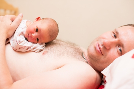 Father and newborn baby daughter cuddlingの写真素材