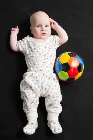 Baby boy playing with a soccer ball on black background  Babies And Childrenの写真素材