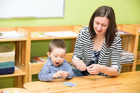 Mother and child boy drawing together with color pencils in preschool at the table in kindergartenの写真素材