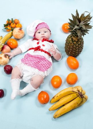 Baby cook girl wearing chef hat with fresh fruits. Use it for a child, healthy food conceptの写真素材