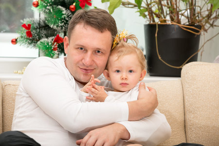 Happy father and baby girl cuddling at home. Use it for a child, parenting or love conceptの写真素材