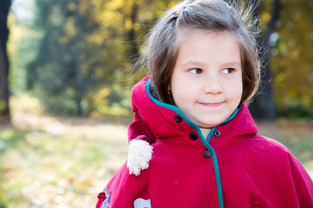 Cute child girl playing with fallen leaves in autumn parkの写真素材
