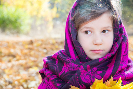 Cute child girl playing with fallen leaves in autumn parkの写真素材