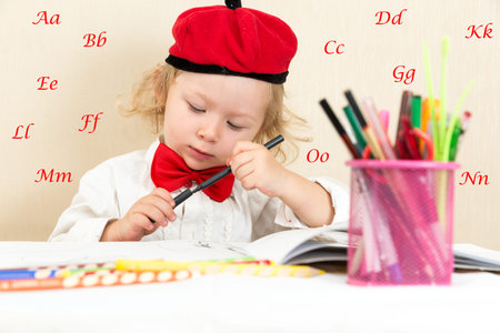 Cute child girl drawing with colorful pencils and felt-tip pen in preschool at table in kindergartenの写真素材