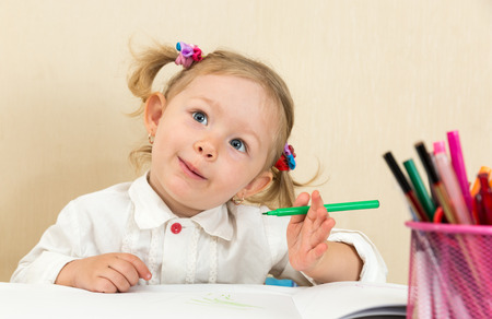 Cute child girl drawing with colorful pencils and felt-tip pen in preschool at table in kindergartenの写真素材