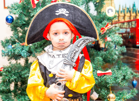 Little boy child dressed as pirate for Halloween  on background of Christmas tree. Kid in carnival...