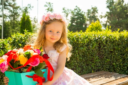 Adorable little child girl with bouquet of flowers on happy birthday. Summer green nature background. Use it for baby, parenting or love conceptの写真素材