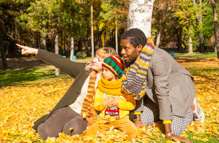 Happy family in autumn park. African American family: black father, mom and child boy on nature in fall.の写真素材