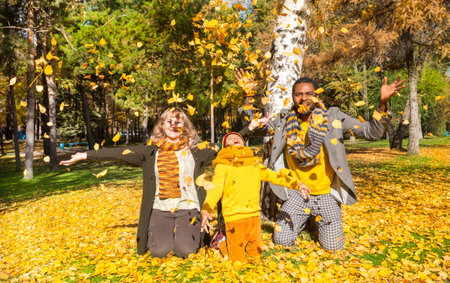 Happy family in autumn park. African American family: black father, mom and child boy on nature in...